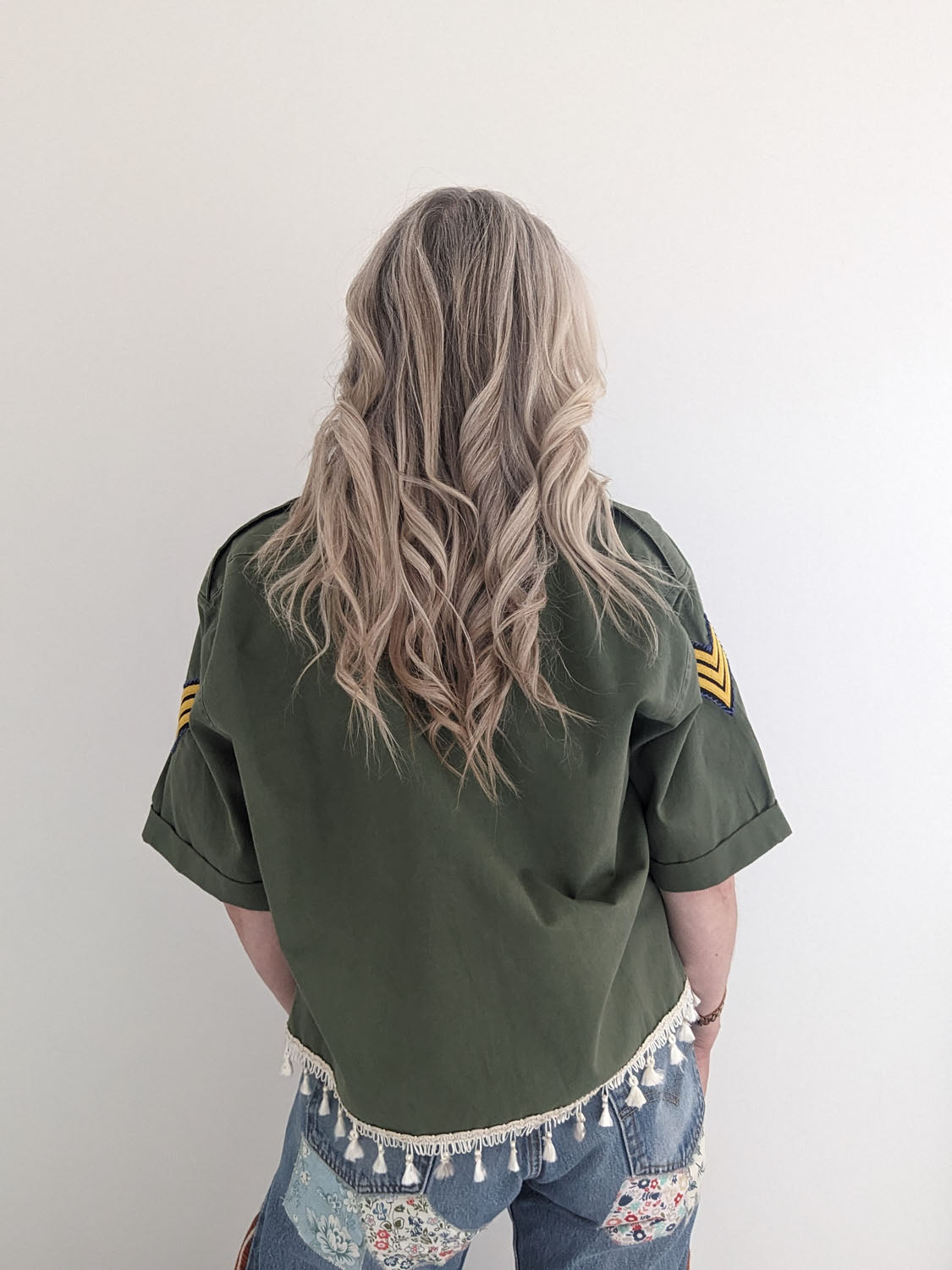 Person wearing a green jacket with tassel details on a plain background