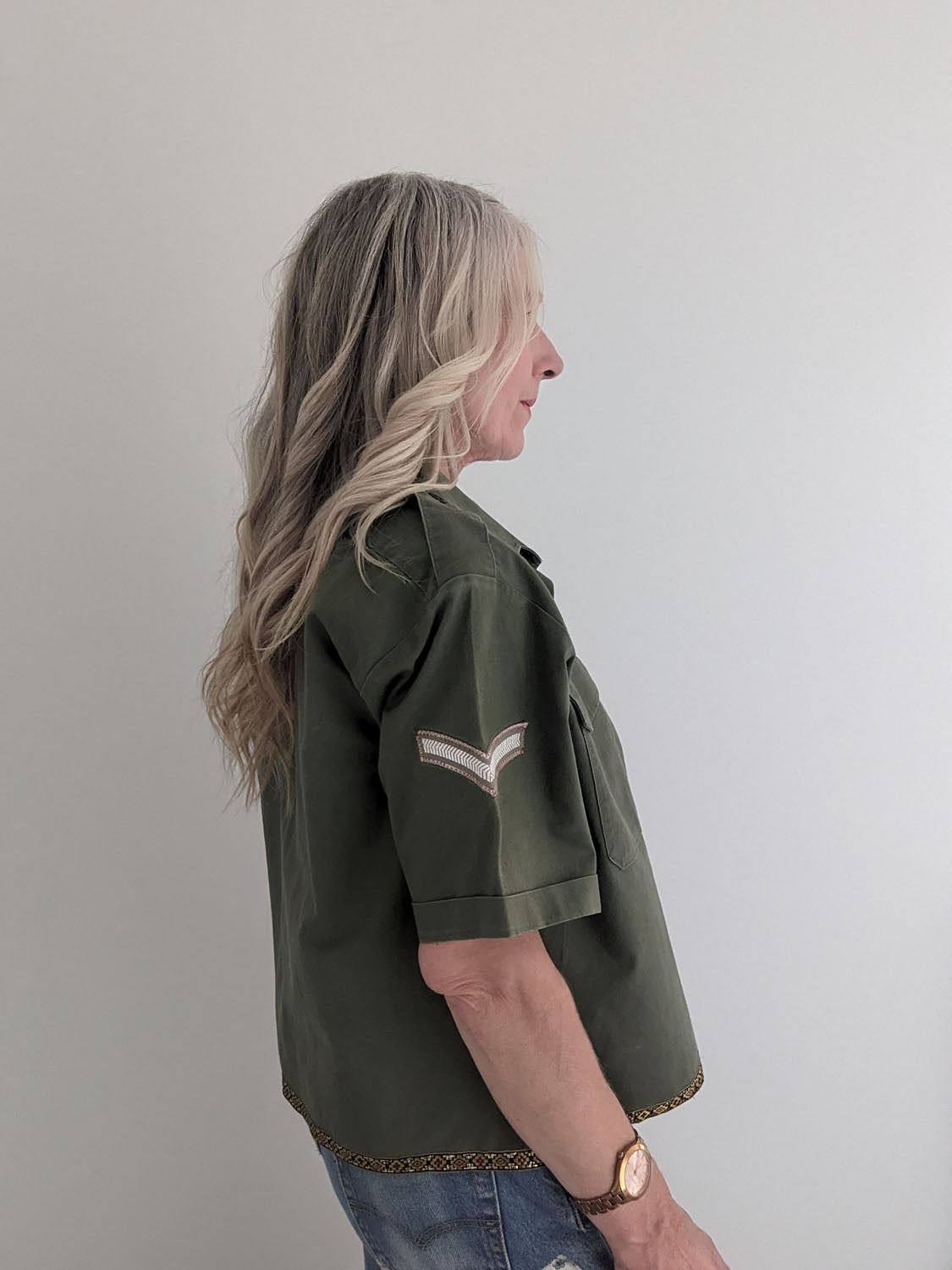 Person wearing a green jacket with a white stripe on a plain background