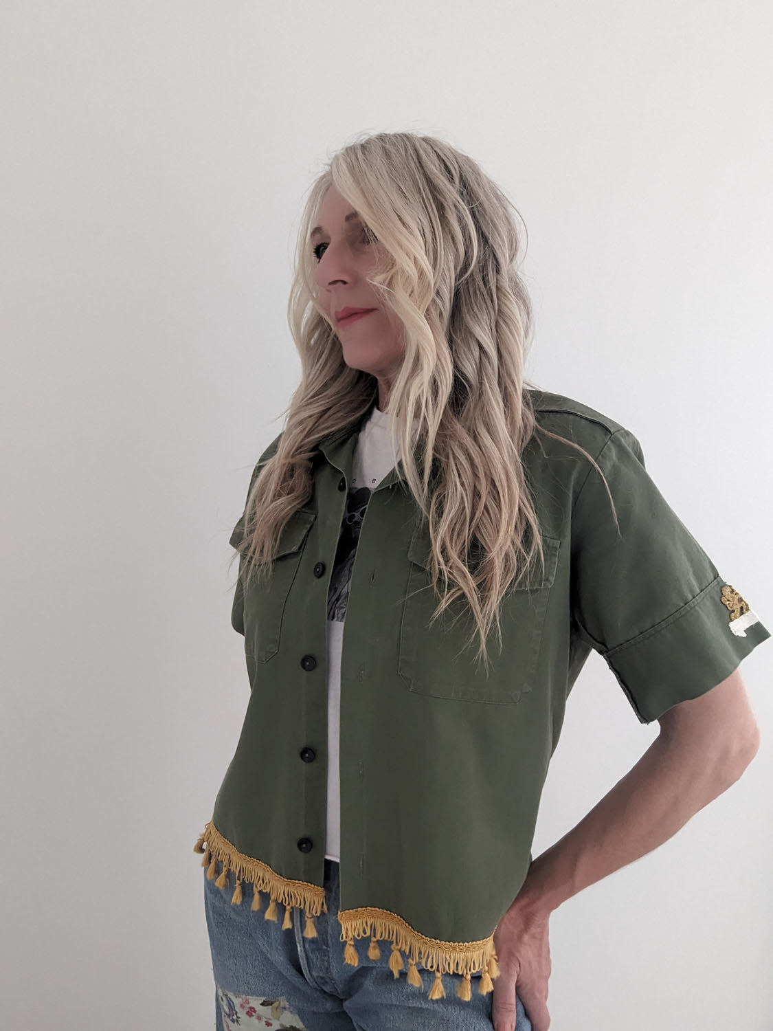 Woman wearing a green army shirt with tassel details on a white background