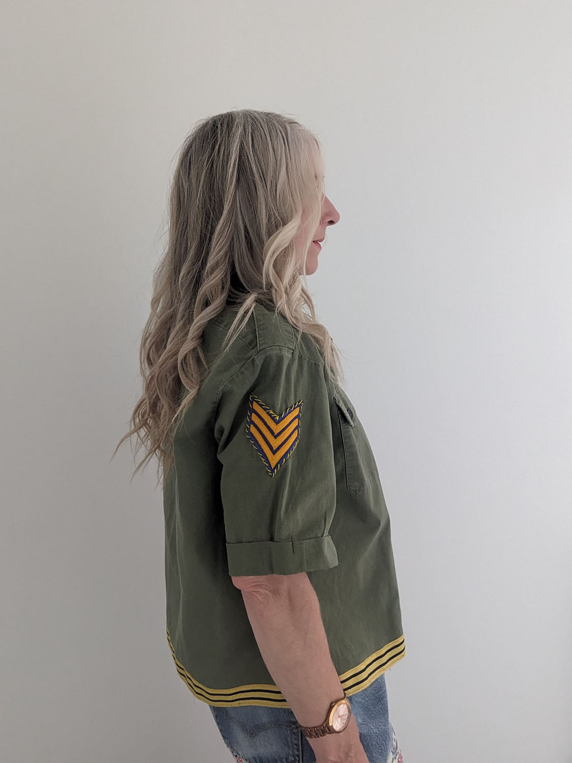 Person wearing a green jacket with yellow accents on a plain background