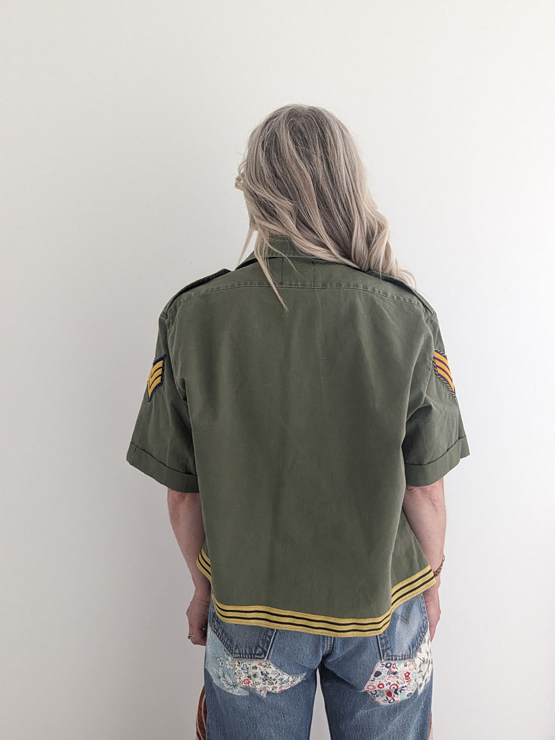 Person wearing a green jacket with yellow stripes on a plain background