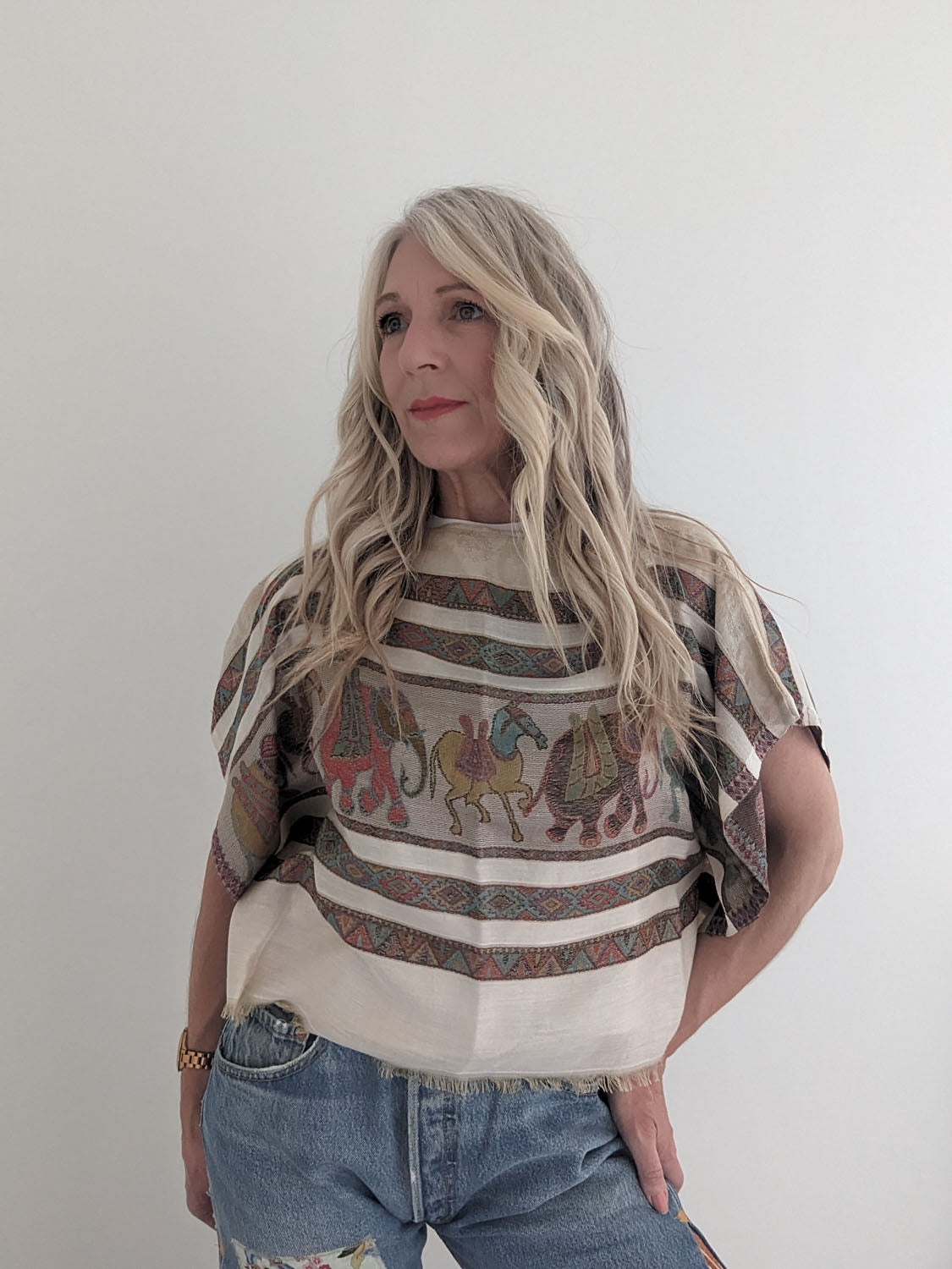 Woman wearing a patterned top with elephants and stripes against a plain background
