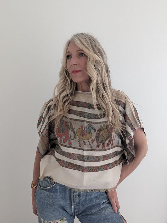 Woman wearing a patterned top with elephants and stripes against a plain background