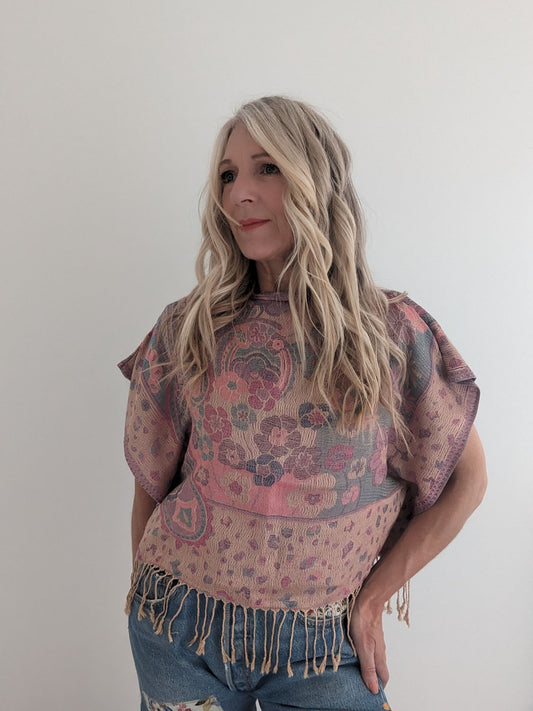 Woman wearing a patterned shawl over a top with a plain background