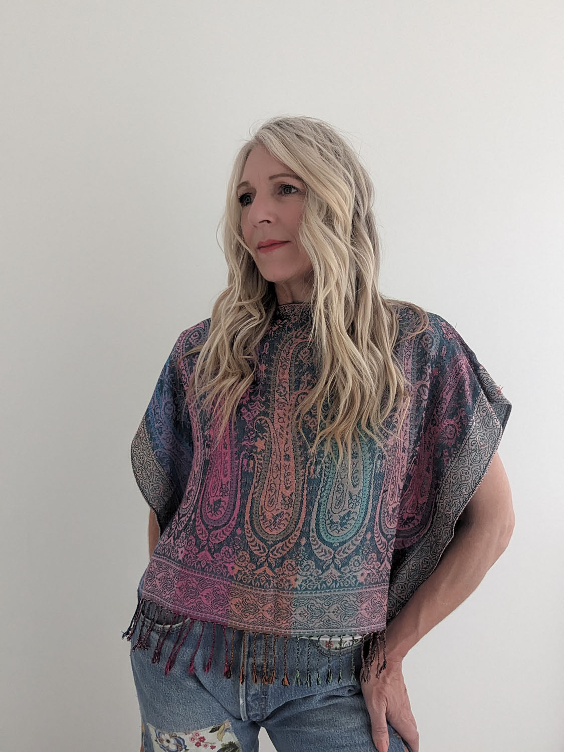 Woman wearing a patterned poncho against a plain background