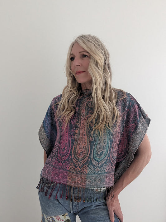 Woman wearing a patterned poncho against a plain background