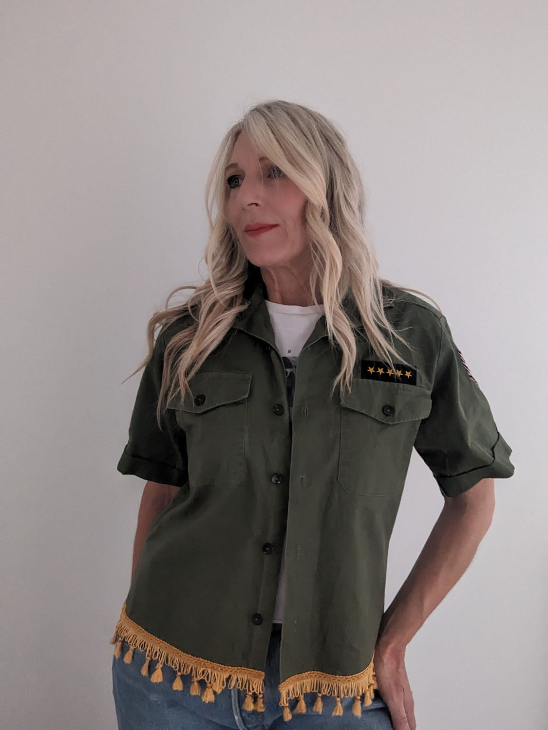 Woman wearing a green jacket with tassel details on a plain background