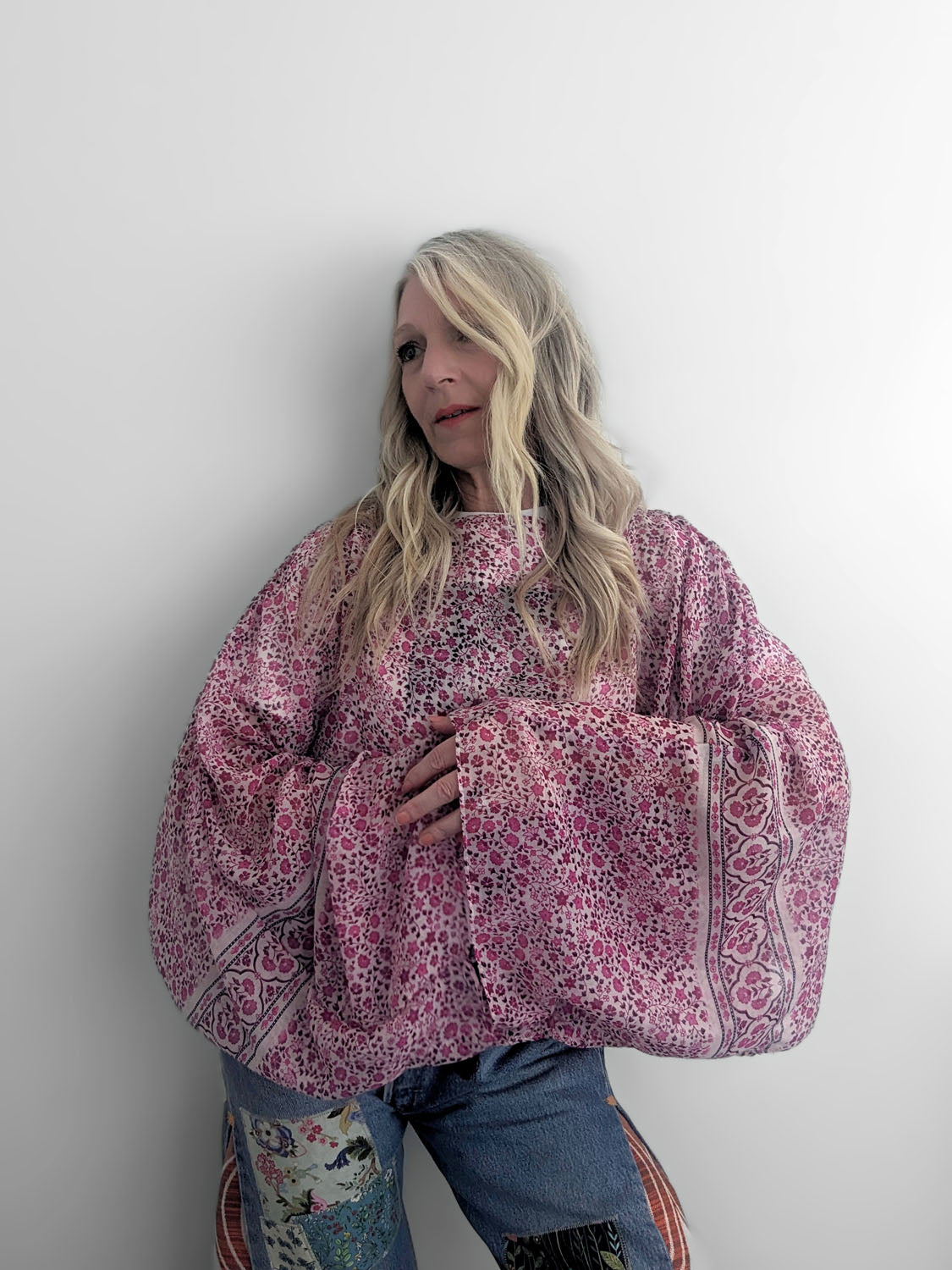 Person wearing a pink floral blouse against a white background