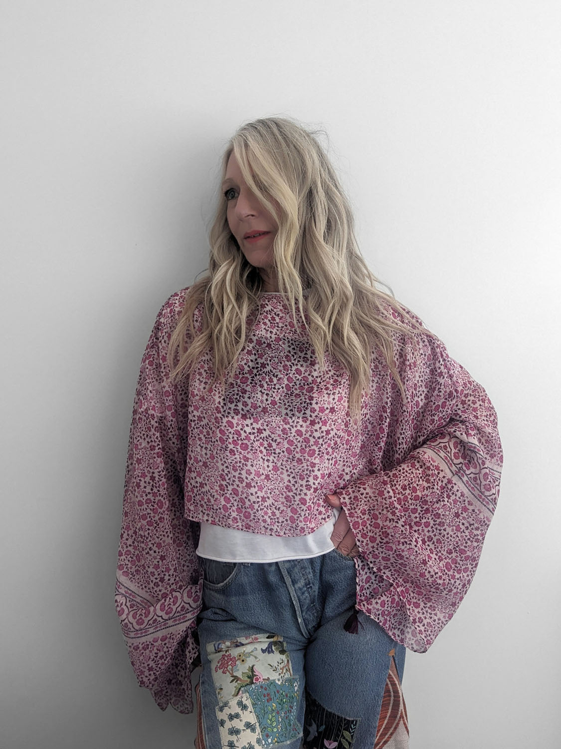 Person wearing a pink floral sweater and jeans against a white background