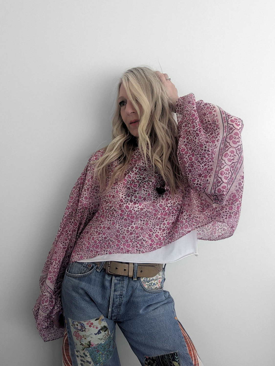 Person wearing a pink patterned shirt and blue jeans against a white background
