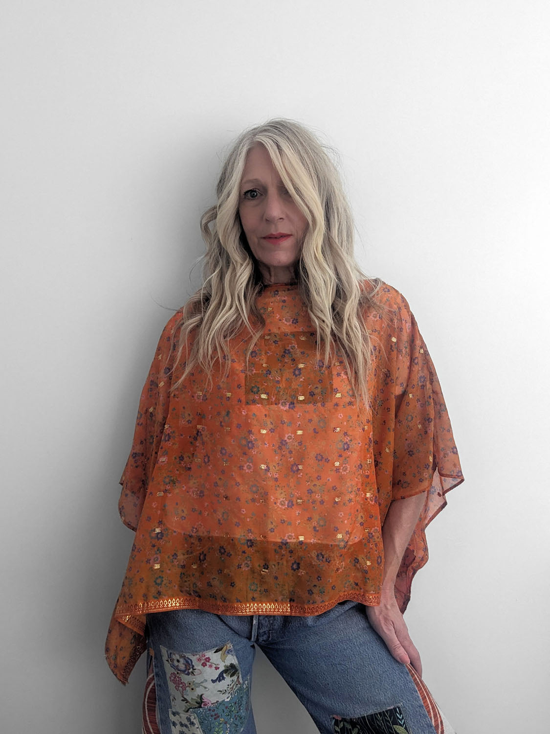Person wearing an orange floral blouse against a plain background
