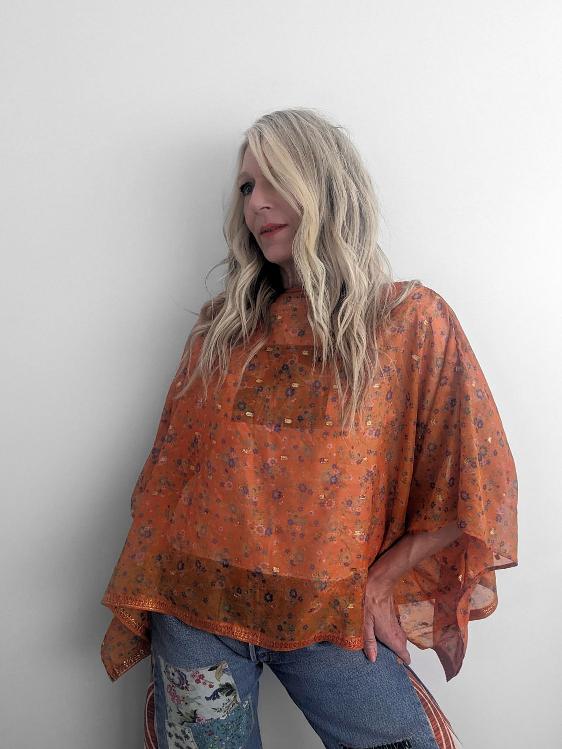 Woman wearing an orange floral blouse against a white background