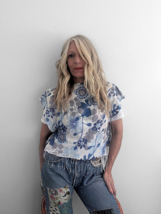 Woman wearing a floral top and jeans against a plain background