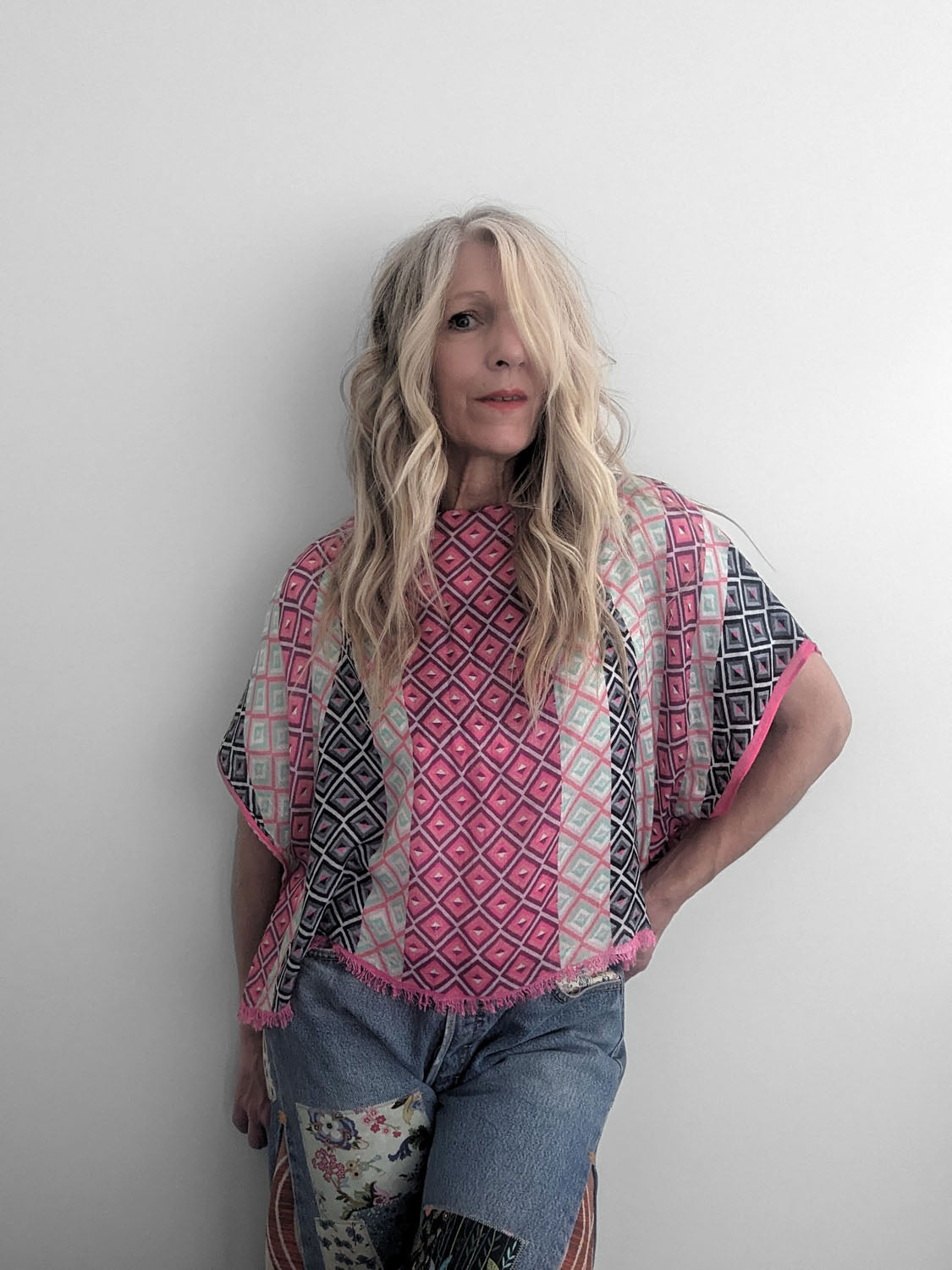 Person wearing a patterned poncho against a plain background